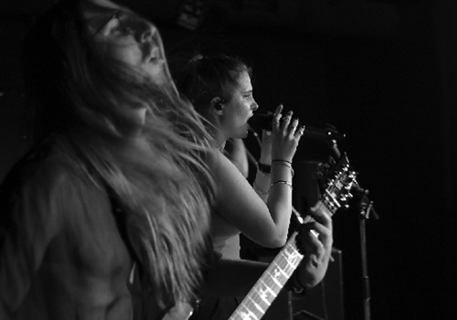 un guitariste au cheveux longs et une chanteuse tenant un micro