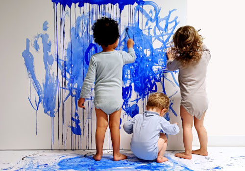 Trois petits enfants peignent un mur