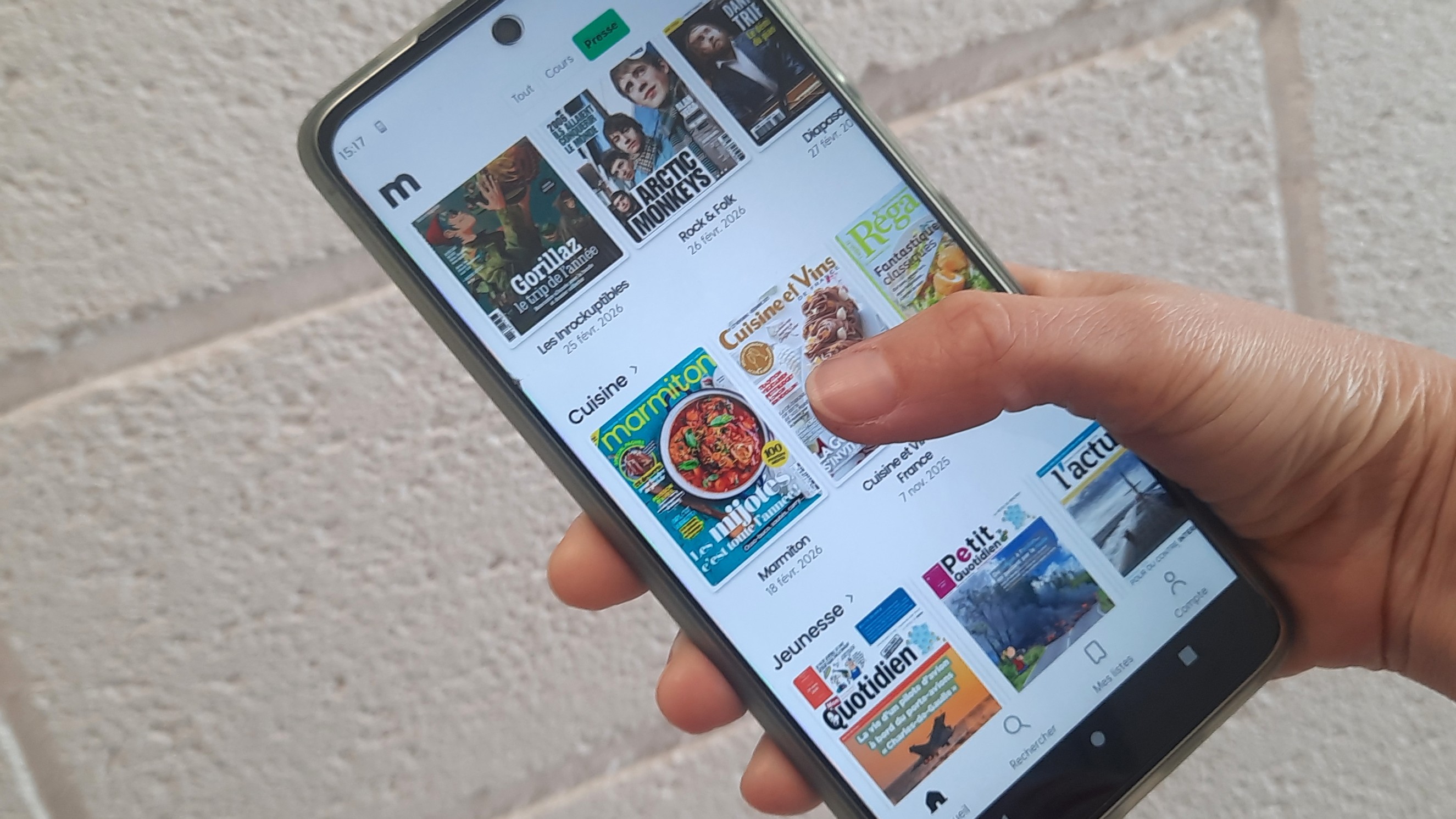 Une main tient un smartphone avec l'application Mozaik 
