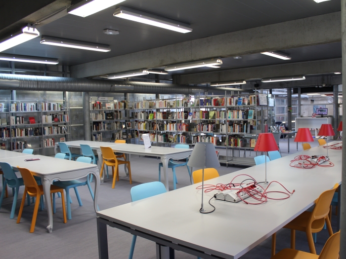Vue de la salle Terrasse : tables de travail au premier plan et étagères au second plan